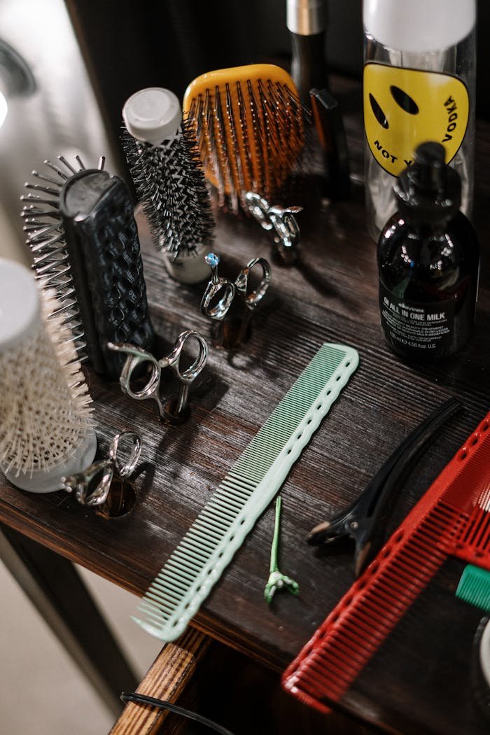 our-services-2 Close-up of diverse barber tools and styling products arranged on a wooden table in a salon.