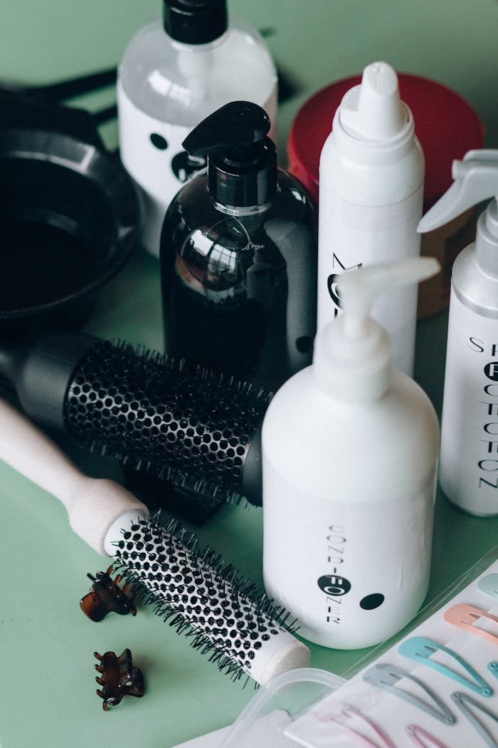 our-services-1 Close-up of hairstyling tools and cosmetic bottles on a green background for salon use.